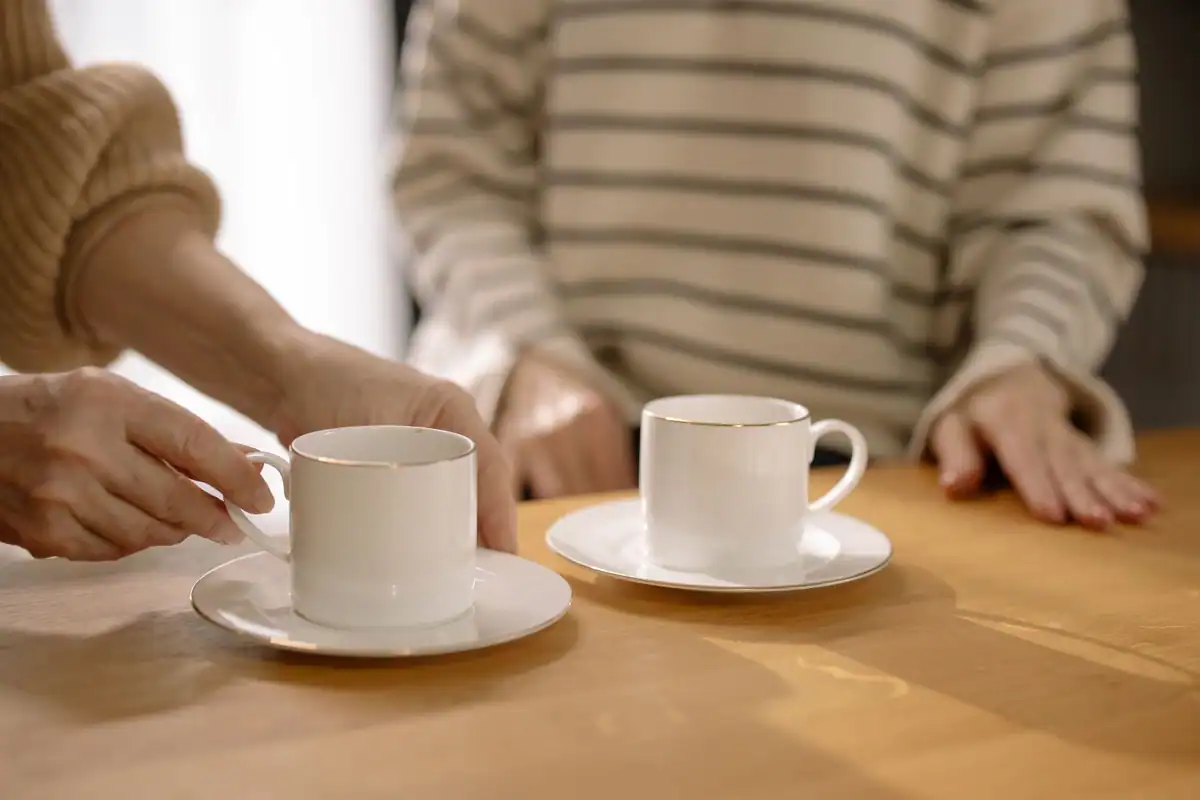 Două căni de cafea pe o masă de lemn, într-o dimineață liniștită acasă