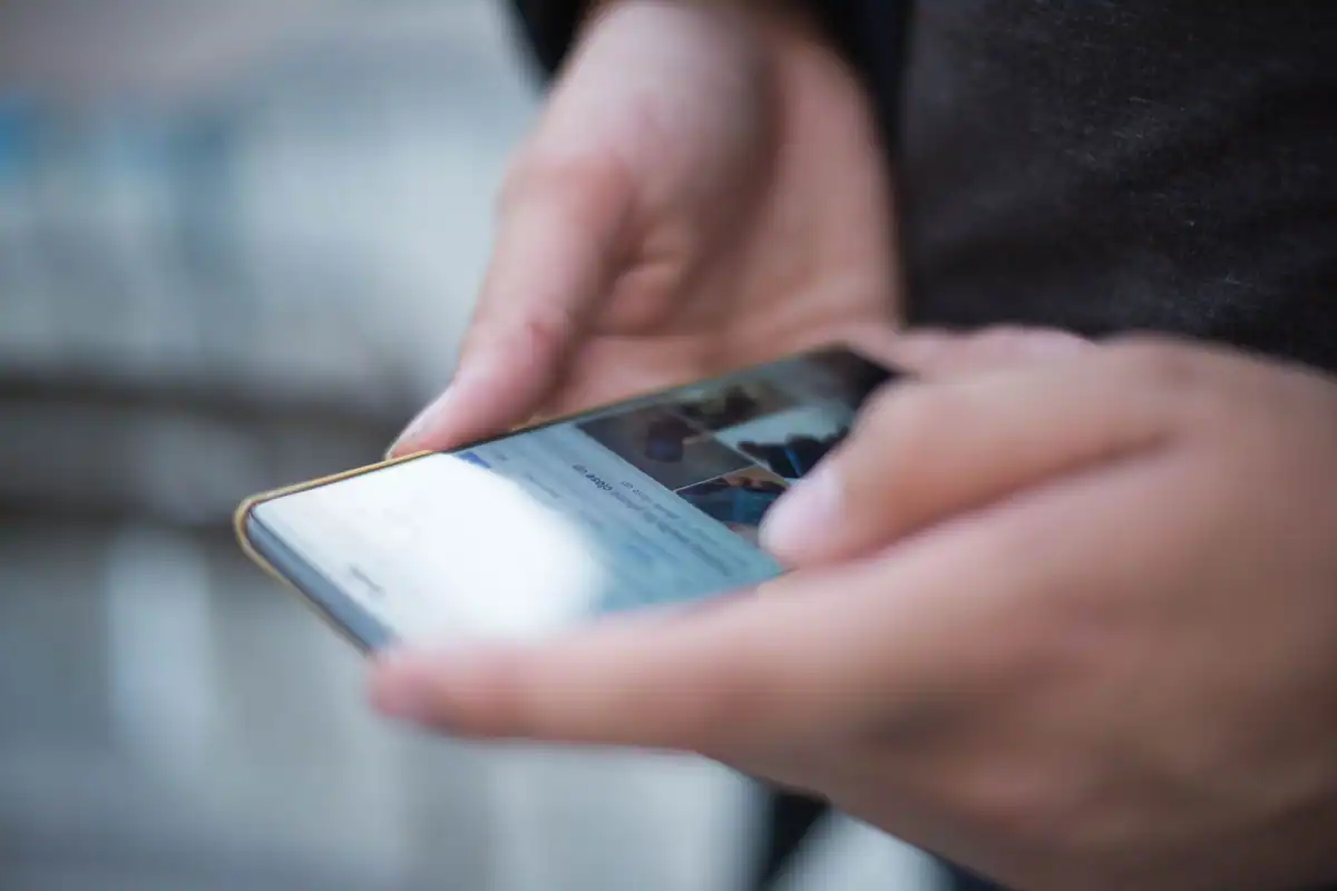 Mâini care derulează rețelele sociale pe ecranul unui telefon