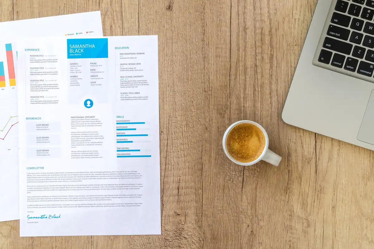 Birou văzut de sus, cu un CV, o cană de cafea și un laptop, în timpul unei căutări