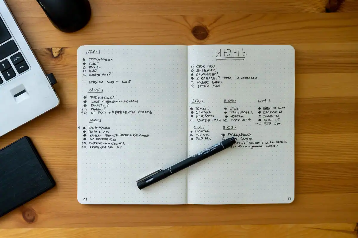 Carnet deschis cu notițe scrise de mână lângă un laptop și un pix
