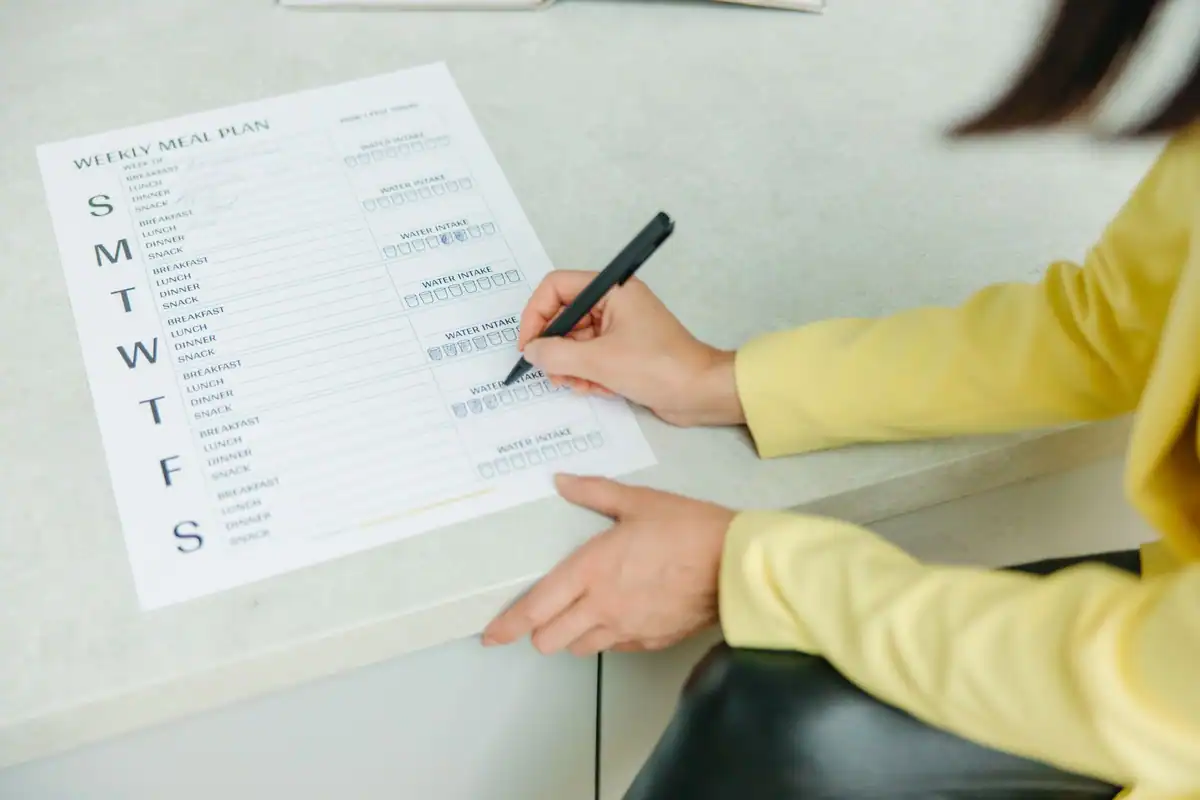 Femeie care bifează o listă săptămânală, obicei de notare zilnică