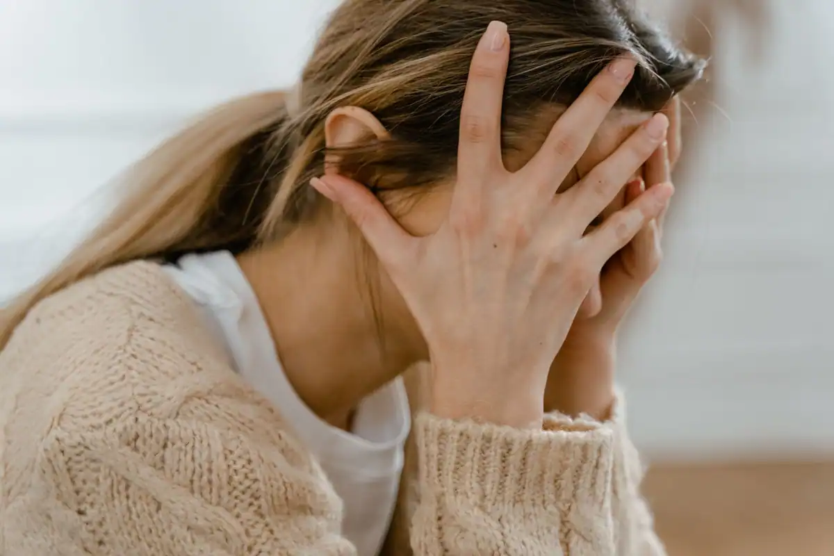 Femeie care își acoperă fața cu mâinile, copleșită de emoții